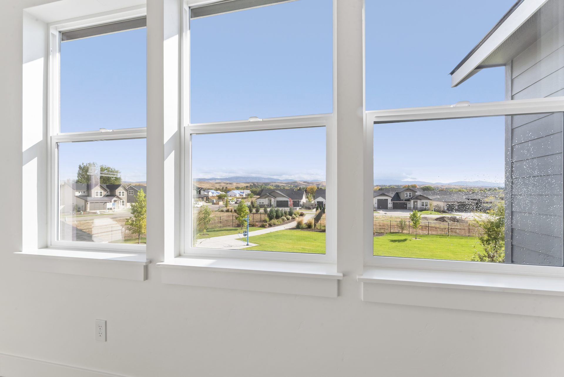 A close up photo through three windows to a view of a neighborhood.