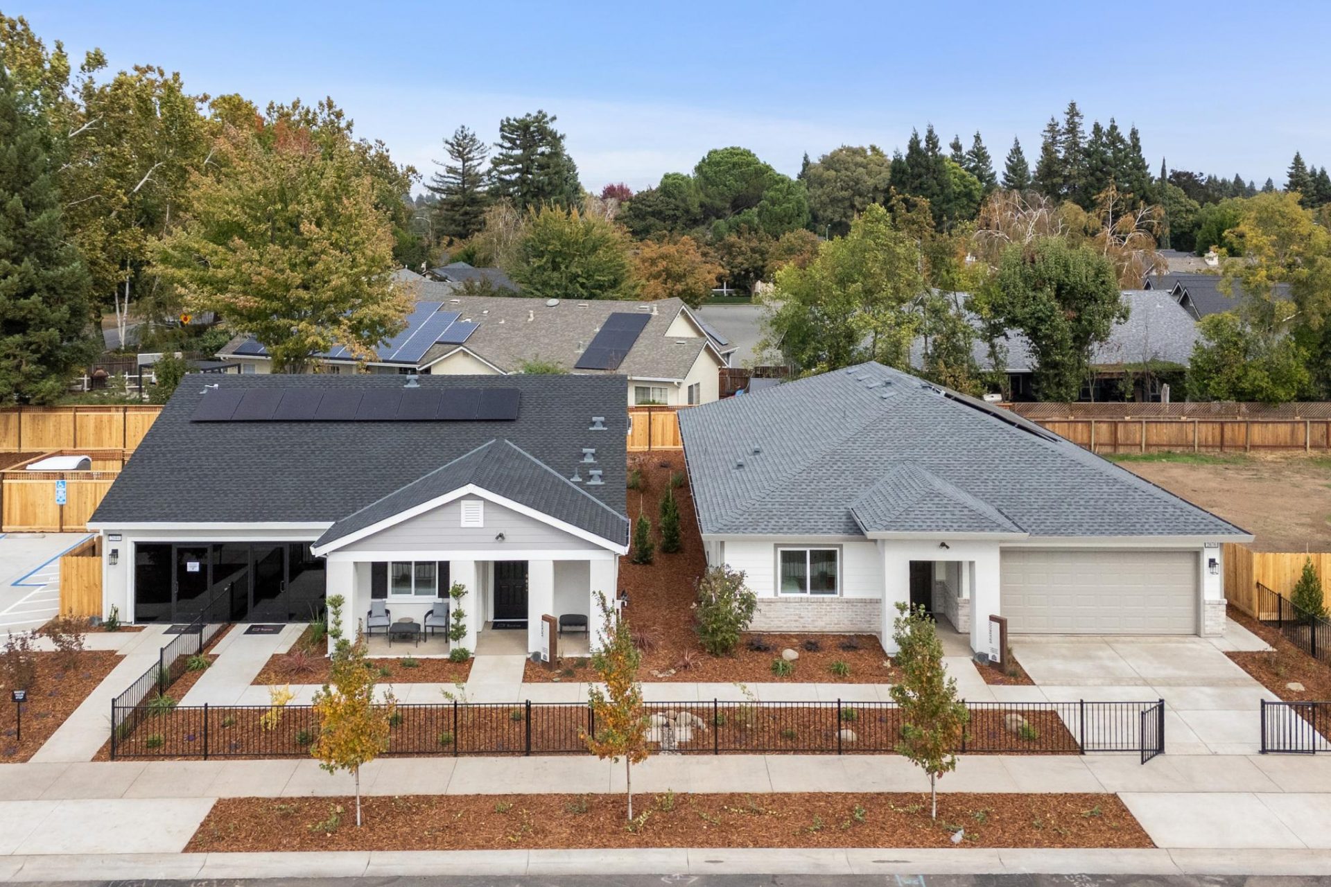 2 craftsmen style exterior elevation single-level homes drone view each with covered front patios, 2 car garages and front landscaping.