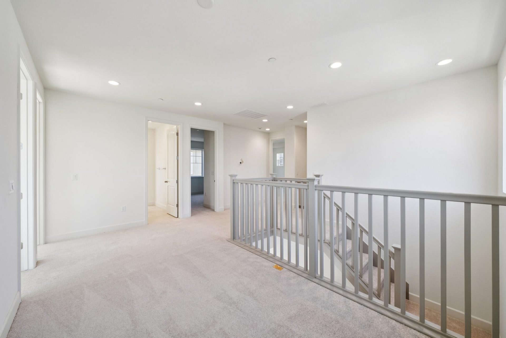 The top landing of a staircase leading to hallways and separate rooms.