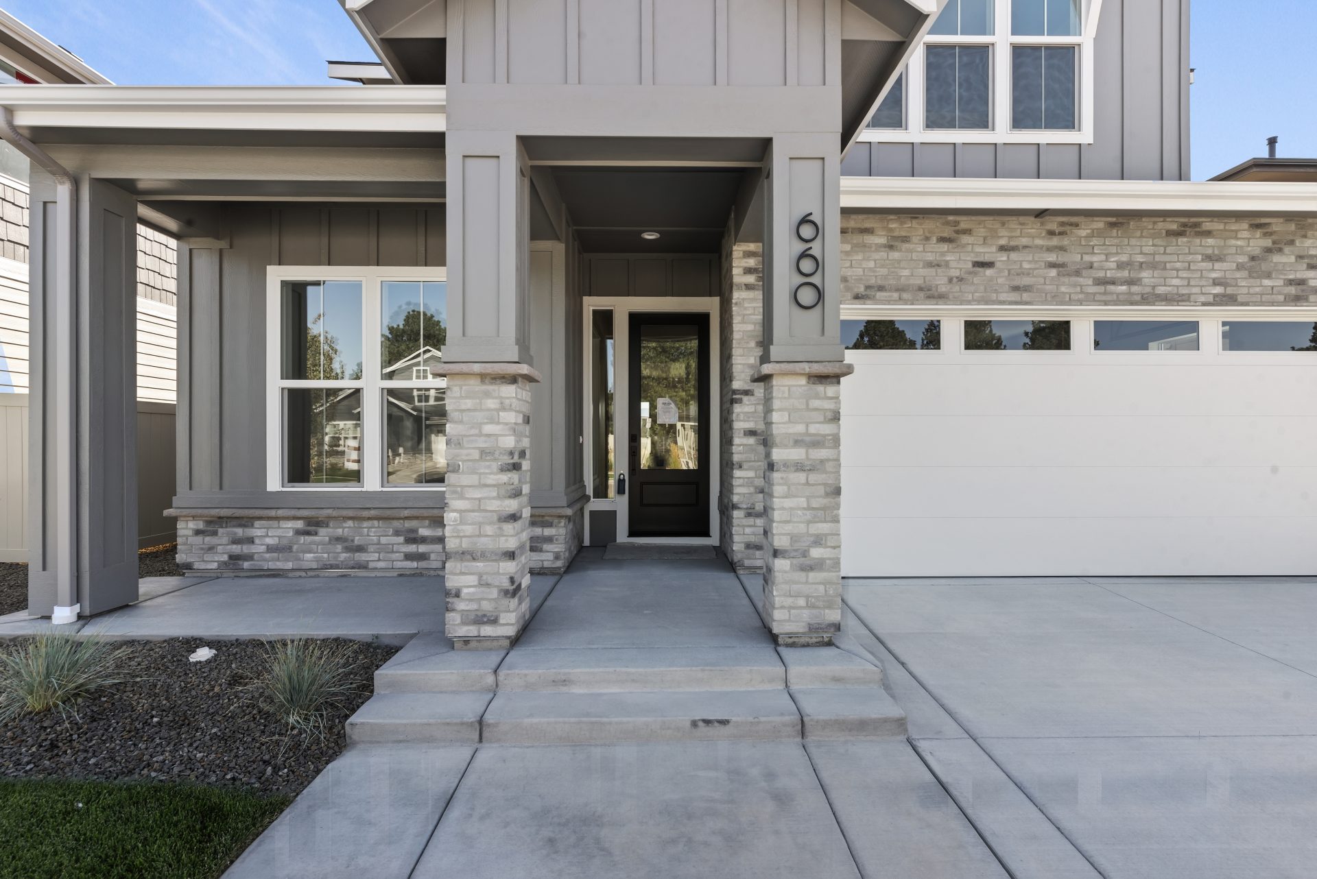 A entry to a home with gray and white paint colors with different gray colored brick stone details.