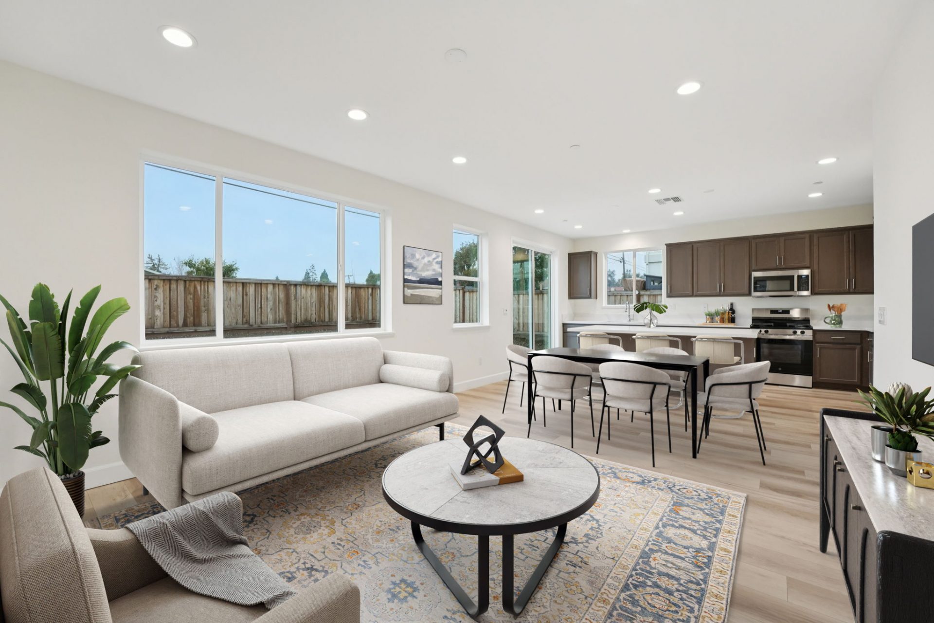 A virtually staged family room and dining room connected to the kitchen. There is a seating area with a coffee table, a dining table with six chairs and various décor items.