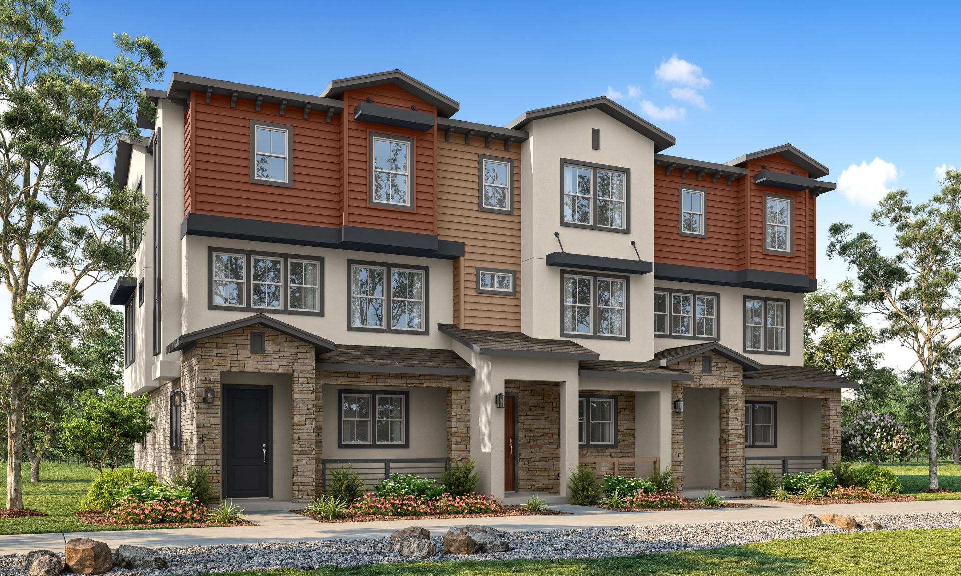 Modern row of three-story townhouses with mixed siding and stone accents, featuring large windows, small front porches, and landscaped greenery under a blue sky