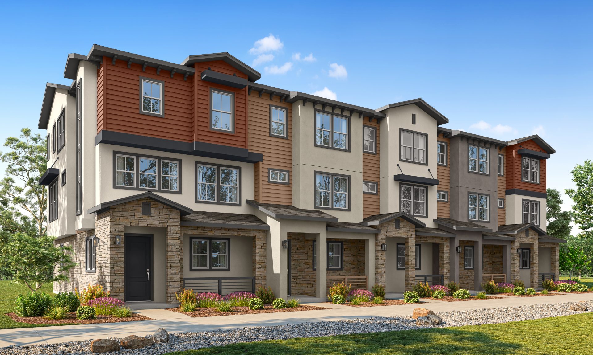 Modern row of three-story townhouses with mixed siding and stone accents, featuring large windows, small front porches, and landscaped greenery under a blue sky