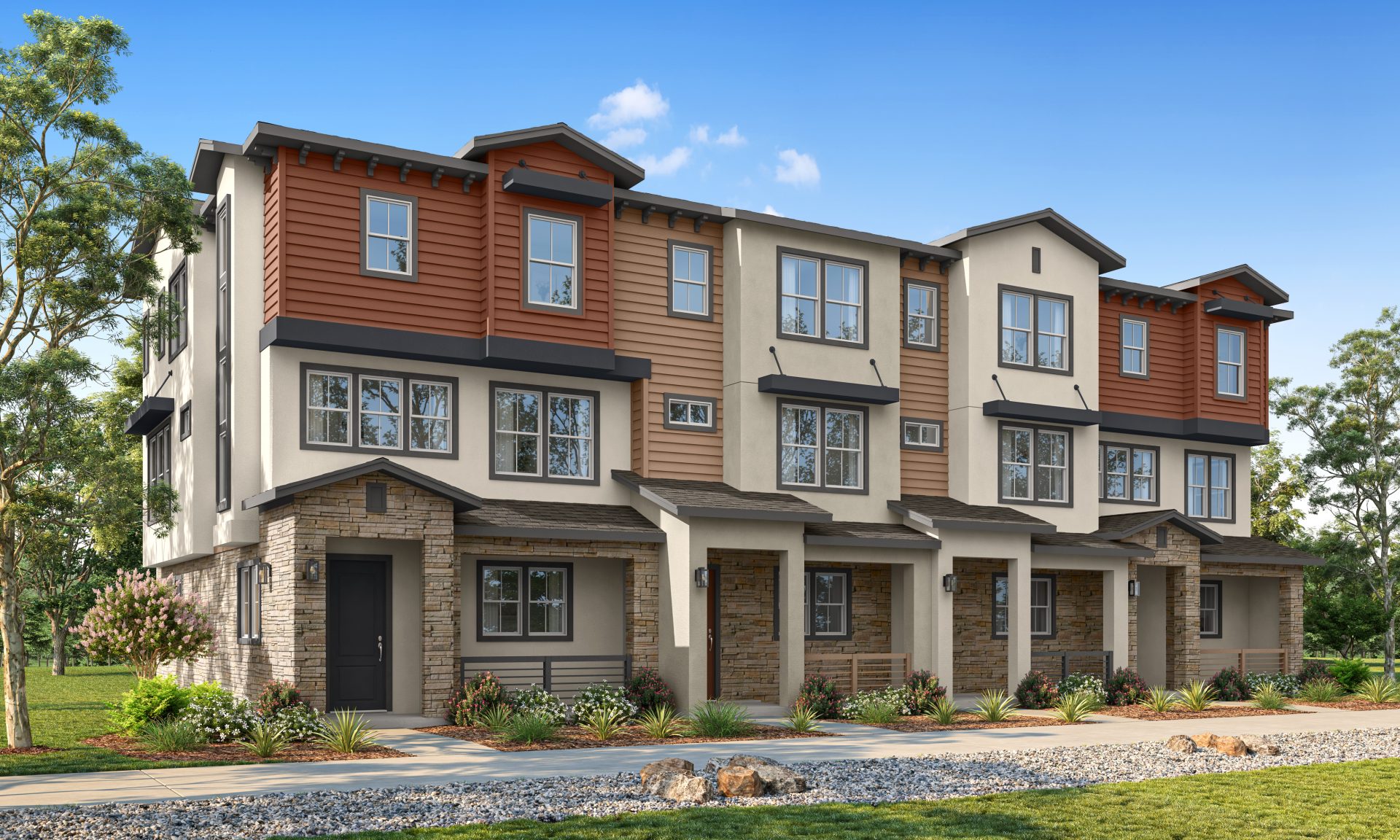 Modern row of three-story townhouses with mixed siding and stone accents, featuring large windows, small front porches, and landscaped greenery under a blue sky
