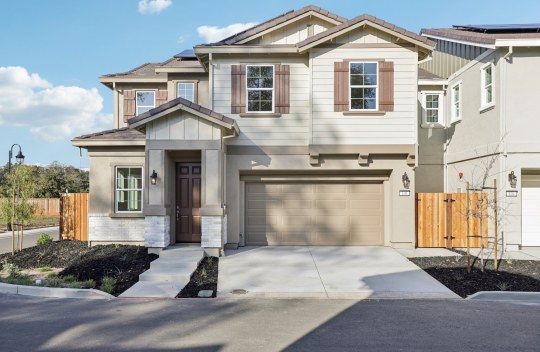 Exterior photo of a two story single family home with a 3 color paint scheme, two car garage, horizontal siding and shutters.