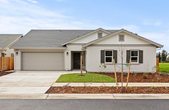 A single story single family home with a 3 color paint scheme, and window shutters.