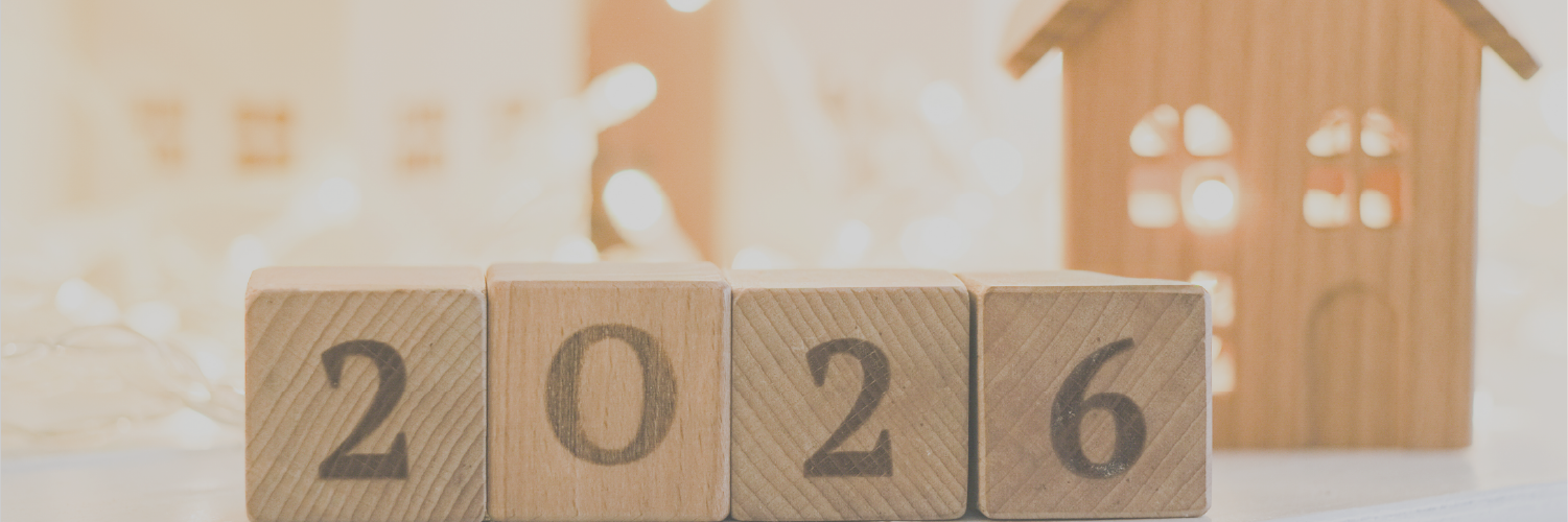 A photo with block letters with 2026 on them and a small wooden block house in the background with light colors.